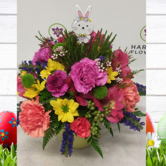 pink alstroemeria, pink carnations, orange carnations, lavender carnations/magenta mini carnations, yellow daisies, green pom pom, berzellia and accented with pink wax flowers, blue statice and a cut bunny pick